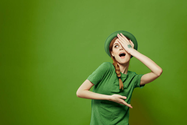 Happy woman with shamrock on St. Patricks Day in green clothes and a hat on her head gesturing with her hands - Photo, Image