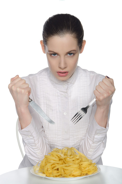 woman with fork, knife and spaghetti, sits - Фото, зображення
