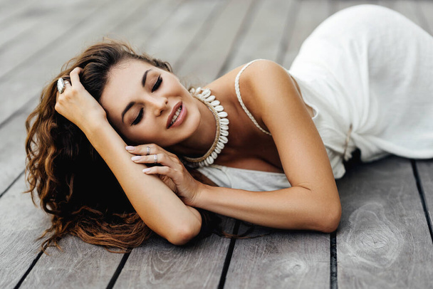 Photo of beautiful lady in white dress laying on the wooden floor,summer accessories. - Valokuva, kuva