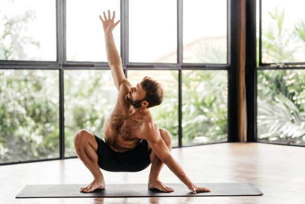 Yoga men workout in studio in front of a window - Φωτογραφία, εικόνα