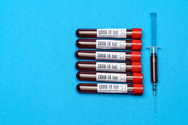 top view of medicine test tubes with blood samples and syringe over blue background - Fotografie, Obrázek