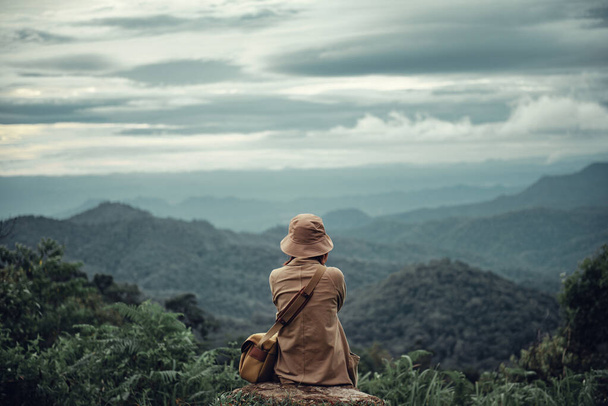 山の雲の空のピークに座っている一人の女性,孤独なシーン,希望を待っています,考えて,それからすべての概念を取得. - 写真・画像