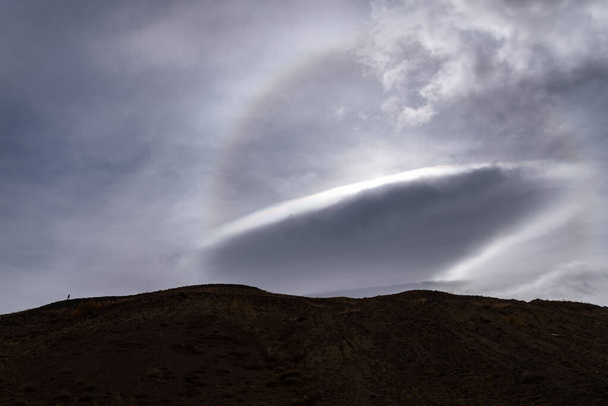 Amazing view of beautiful cloud patterns and circular sun halo in the sky above the mountains - Fotoğraf, Görsel