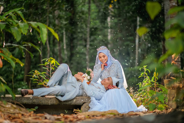 Fotografování ze svatby. Nevěsta a ženich nosí dětskou modř Malajština tradiční oblečení v lese. - Fotografie, Obrázek
