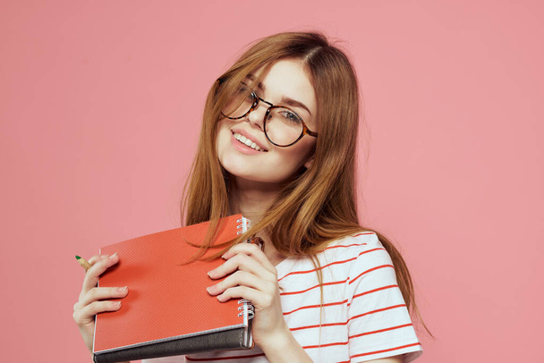 Νεαρή φοιτήτρια με βιβλία για ροζ γυαλιά φόντου σε ινστιτούτο εκπαίδευσης προσώπου - Φωτογραφία, εικόνα