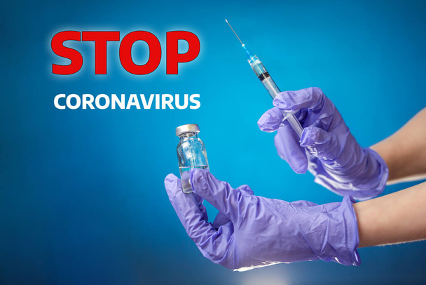Arrêtez le coronavirus. La main du médecin dans des gants médicaux contient un flacon et une seringue injectable. Fond bleu. Le concept de coronavirus, vaccins et santé. - Photo, image