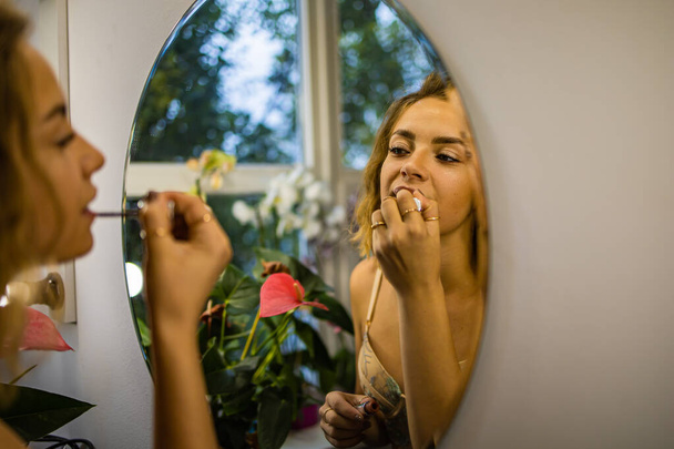 Egy gyönyörű fiatal nő a tükör előtt Színek Ajakrúzs - Fotó, kép