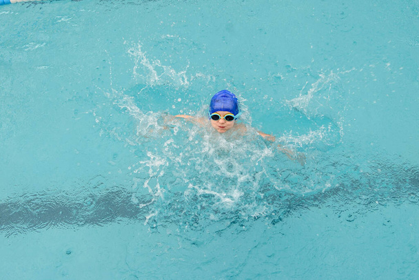 vista superior de un niño de 7 años jugando y nadando en la piscina - Foto, Imagen