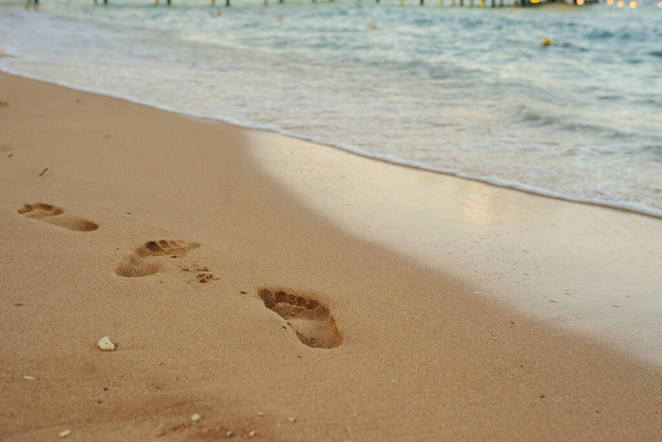 Ślady ludzkich stóp na piasku w pobliżu wody na plaży - Zdjęcie, obraz