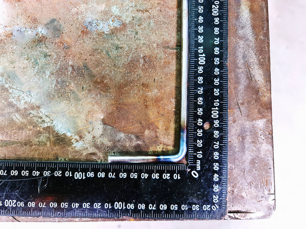 Проверка перпендикулярности изогнутого стержня из нержавеющей стали на старом ржавом металлическом столе - Фото, изображение