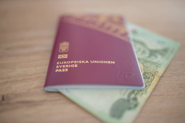 Sweden Passport with a Blurry Twenty Thai Baht Bill Partially Inside - Fotó, kép