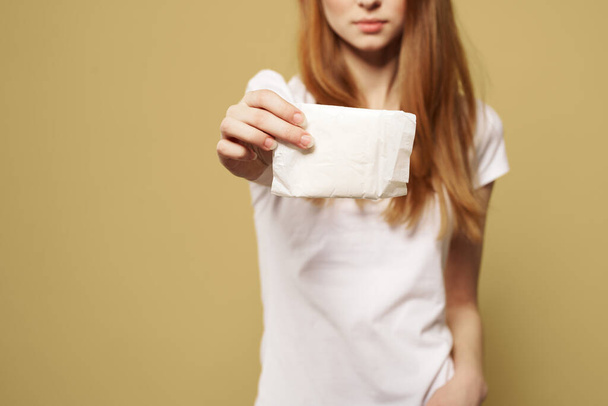 Girl with pad on beige background menstruation critical days cropped view of white t-shirt - Φωτογραφία, εικόνα