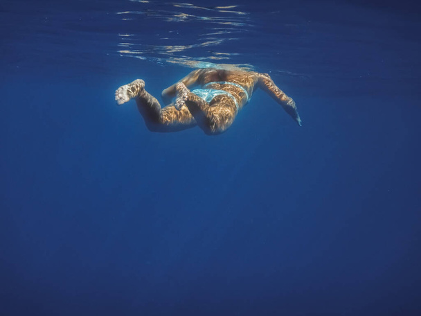 женщина в бикини плавает на поверхности в голубом море на отдыхе - Фото, изображение