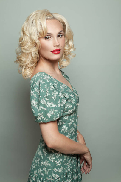 Perfektní žena s make-upem a blond kudrnaté vlasy na sobě zelené šaty na světle zelené banner pozadí - Fotografie, Obrázek