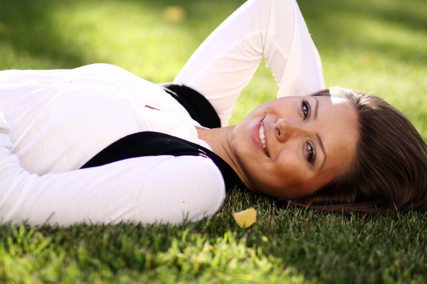Young woman lying on a green lawn - Foto, imagen