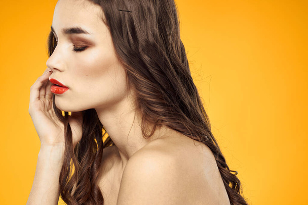 beautiful brunette red lips bare shoulders skin care yellow background - Photo, Image