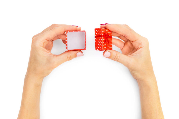 Γυναικεία χέρια ανοίγουν ένα μικρό κουτί δώρου σε λευκό. Άνω όψη. - Φωτογραφία, εικόνα