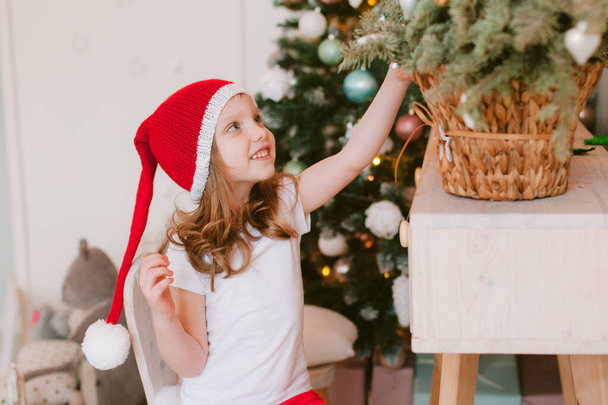 Feliz niña alegre en sombrero de santa. En Navidad. Año nuevo 2021 - Foto, Imagen