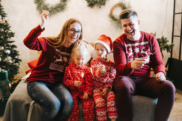 Fröhliche Familie mit Wunderkerzen feiert Weihnachten zu Hause - Foto, Bild