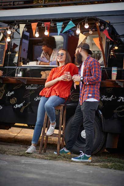 młody miejski kaukaski para flirt przed zmodyfikowane ciężarówki dla mobilnych fast food serwisu - Zdjęcie, obraz