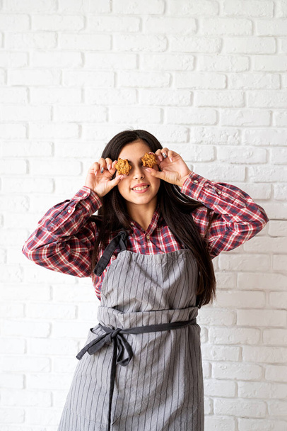Happy woman in apron holding star shaped cookies in front of her eyes - Foto, Bild