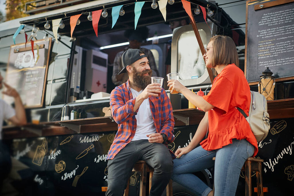 young caucasian couple toasting in front of modified truck for fast food service - Fotoğraf, Görsel