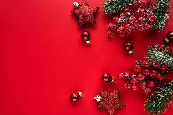 Christmas composition. Christmas red decorations, fir tree branches on red background. Flat lay, top view, copy space - Photo, Image