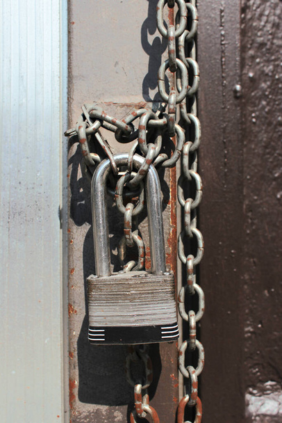 Lock with chain on a closed door. Closed on a chain with a lock a public place in the city centre. - Φωτογραφία, εικόνα