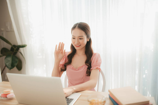 Güzel Asyalı genç kadın dizüstü bilgisayar kullanıyor. Sabahları evden çalışıyor. - Fotoğraf, Görsel