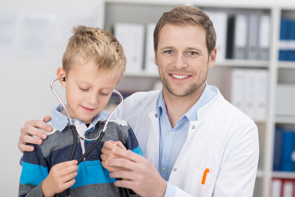 Friendly male doctor examining a young boy - Фото, зображення