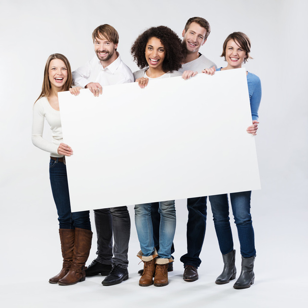 Group of happy young people with a blank sign - Фото, изображение