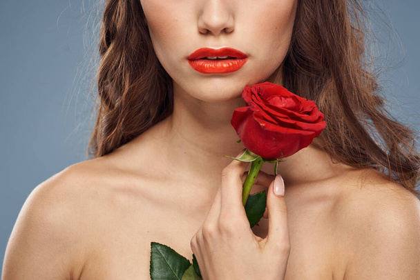 γυναίκα με ένα τριαντάφυλλο στα χέρια της γυμνοί ώμοι βραδινό μακιγιάζ κόκκινα χείλη - Φωτογραφία, εικόνα