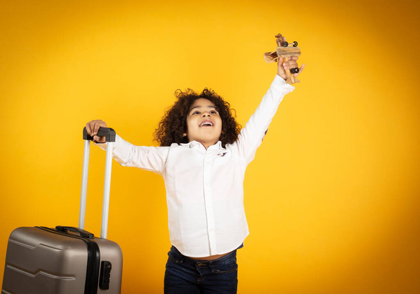 мальчик с чемоданом на желтом фоне, концепция путешествия - Фото, изображение