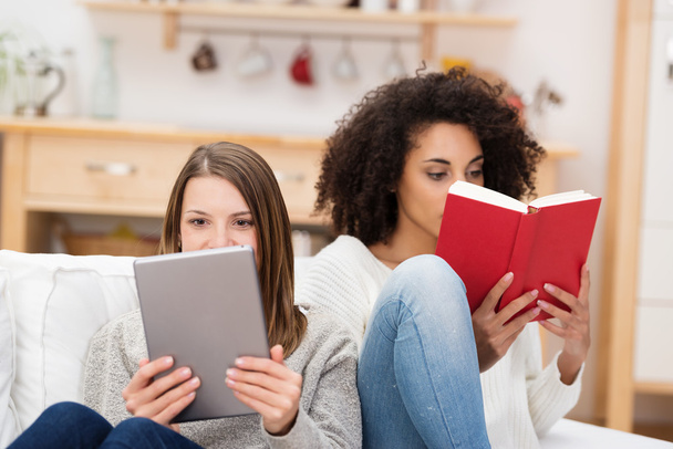Two young women relaxing together reading - Foto, imagen