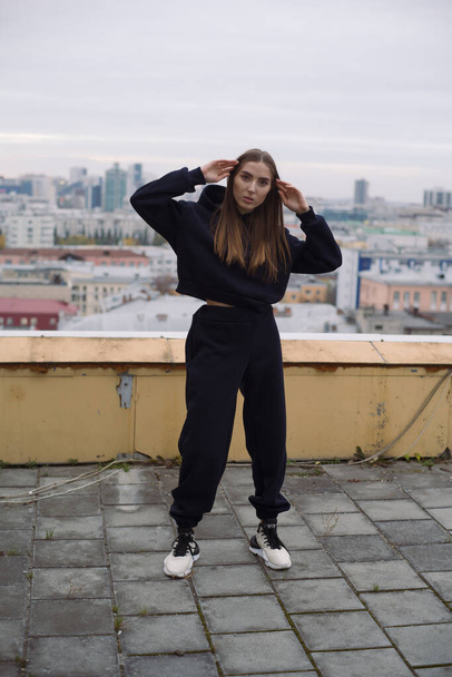 Full height photo of young woman, standing on roof of tall building in large city. - Valokuva, kuva