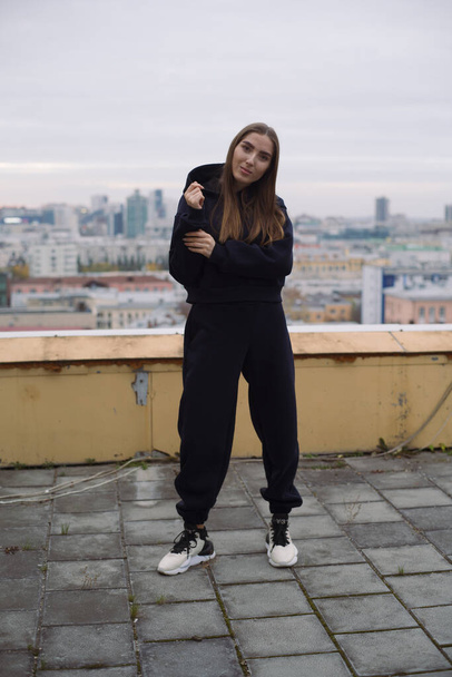 Full height photo of young woman, standing on roof of tall building in large city. - Valokuva, kuva