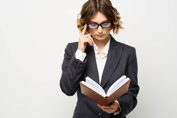 Business woman with notepad and glasses work light background cropped view of suit model. - 写真・画像