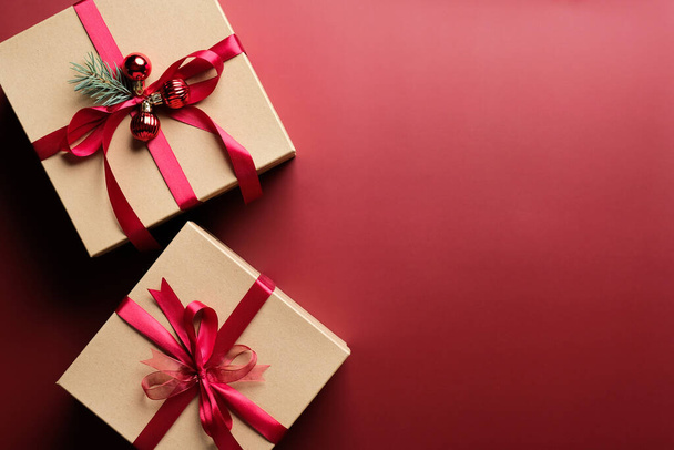 Gift boxes with red ribbon bow on marsala red background with copy space. Christmas presents, gift boxes, surprises concept. Flat lay, top view. - Φωτογραφία, εικόνα