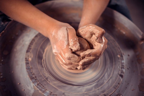 Le mani di vasai sono modellate una tazza da un'argilla. Il processo di creazione di ceramica su una ruota vasai. Il maestro ceramista lavora nel suo studio. Primo piano, solo le mani. Stoviglie da argilla proprie mani. - Foto, immagini