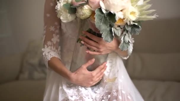 la novia sostiene un jarrón con un ramo de bodas en sus manos - Imágenes, Vídeo