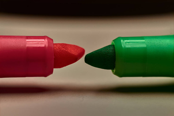 Las puntas de dos marcadores fluorescentes, uno rojo y otro verde, colocados uno frente al otro - Foto, imagen