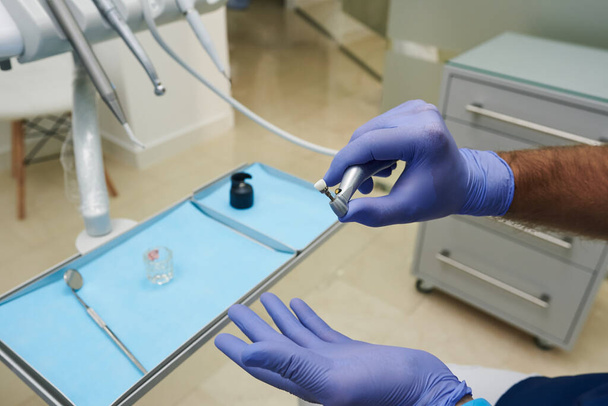 Bir dişçinin ellerini aletleriyle kapatın. Mavi lateks eldiven giyiyor.. - Fotoğraf, Görsel