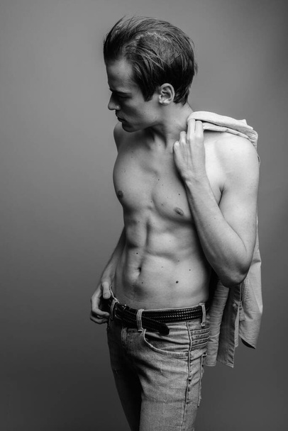 Young handsome man shirtless against gray background - Foto, afbeelding