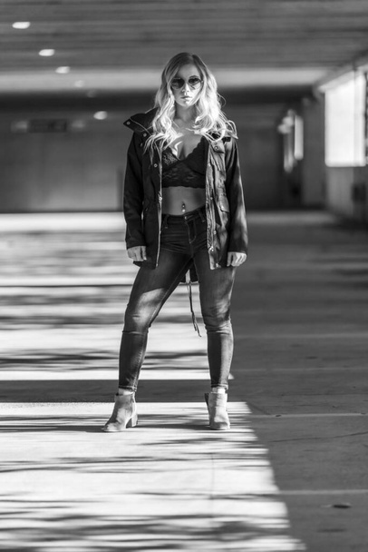 A gorgeous blonde model poses in a parking deck on an autumn day - Foto, imagen
