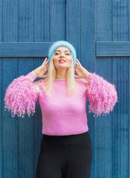 Гарна блондинка в рожевому светрі і синьому вовняному капелюсі, зимовий сезон. Жіночий одяг, модна концепція
 - Фото, зображення