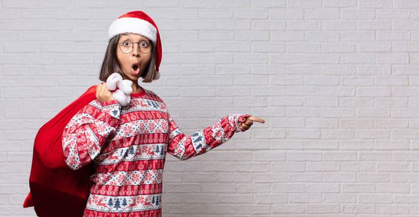 young woman christmas concept against brick wall - 写真・画像