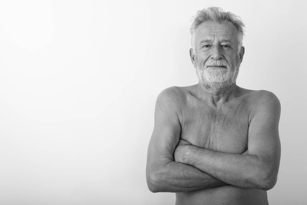 Studioaufnahme eines gutaussehenden, bärtigen Mannes ohne Hemd mit verschränkten Armen vor weißem Hintergrund - Foto, Bild