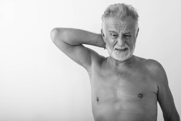 Studio záběr pohledný starší vousatý muž s bolestí krku bez košile proti bílému pozadí - Fotografie, Obrázek
