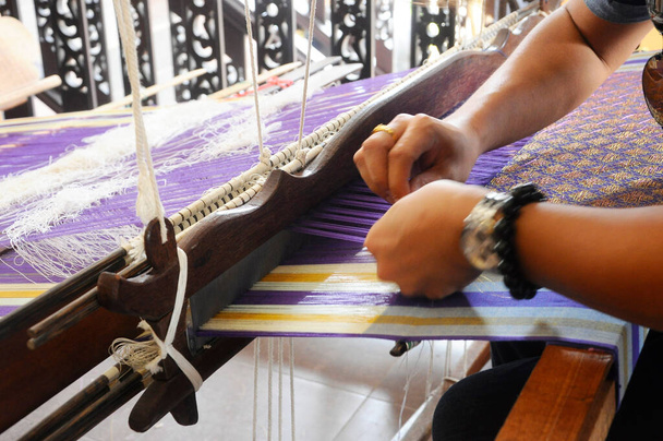 Bir adam şarkı örmek için geleneksel dokuma makineleri kullanıyor.. - Fotoğraf, Görsel