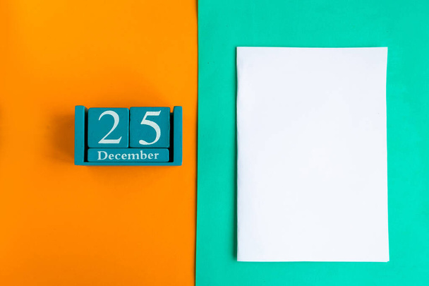 25 december. Blauwe kubus kalender met maand en datum en witte mockup blanco op kleur achtergrond. - Foto, afbeelding